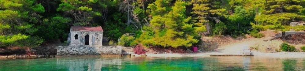 Scenic bay of Kalamos island with clear water and forested hills.
