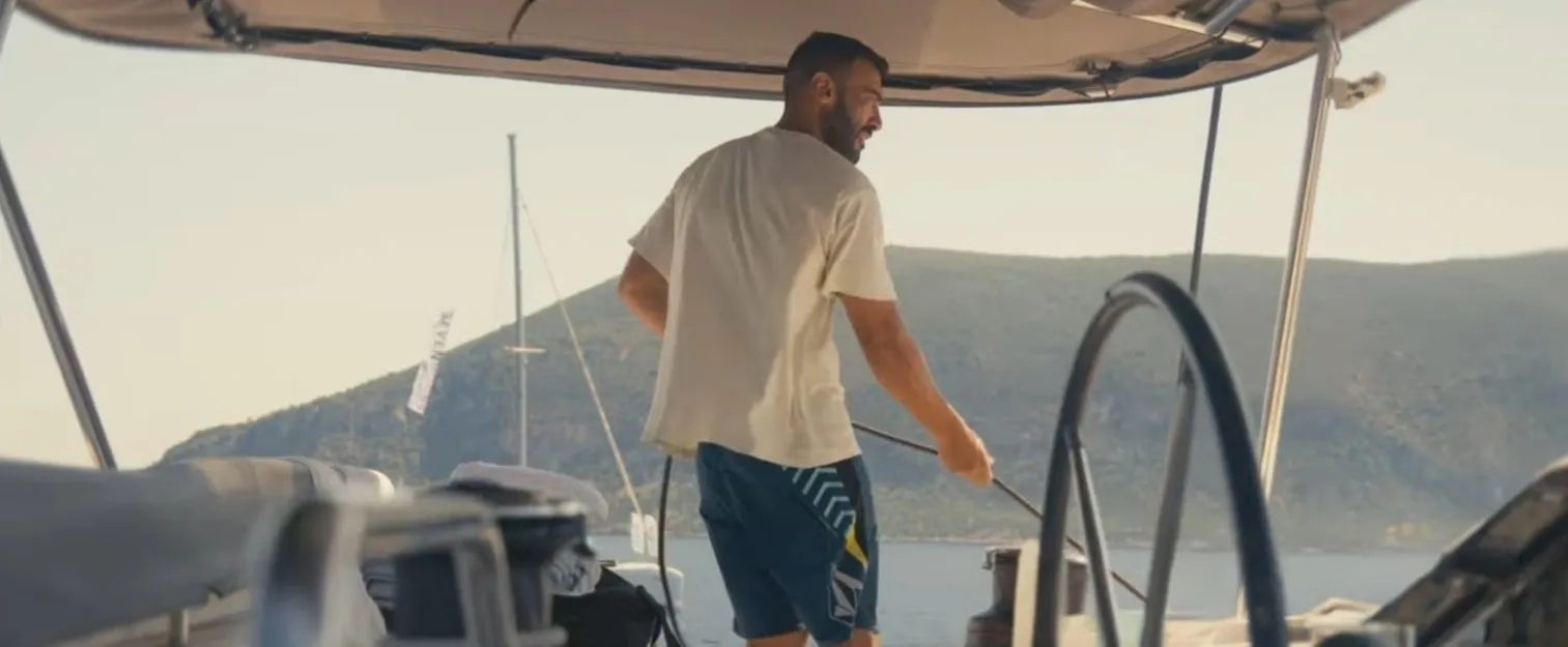 Skipper trimming the sails onboard a catamaran.