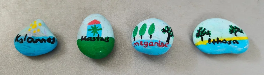 Hand-painted stones labeled Kalamos, Kastos, Kioni, and Ithaca representing Ionian destinations.